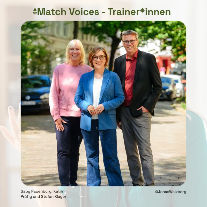 Drei Trainer*innen der Initiative Match Voices stehen lächelnd in einer urbanen Umgebung und repräsentieren den Fußball.