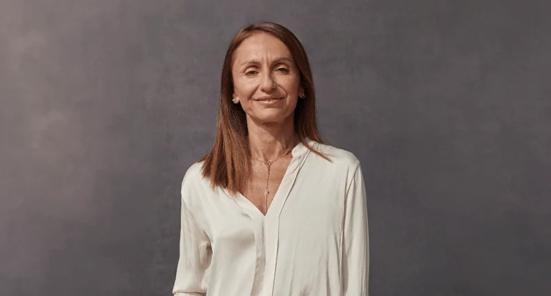 Alice-Mascia steht lächelnd vor einem neutralen Hintergrund und verkörpert die Vielfalt und Leidenschaft des Fußballs.