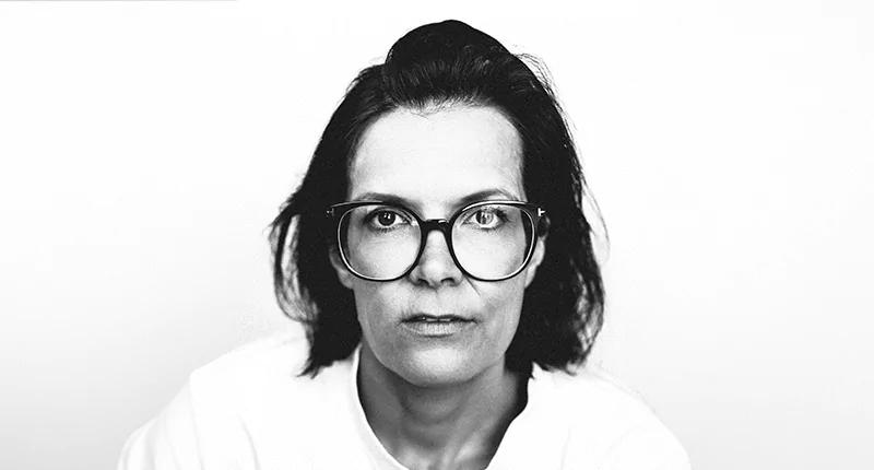 Dr. Anne-Katrin Huebel blickt ernst in die Kamera und verkörpert den Wandel im Fußball für mehr Diversität und Inklusion.