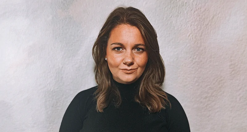 Jessica Stommel präsentiert sich in einem eleganten schwarzen Oberteil vor einem neutralen Hintergrund und verkörpert die Veränderungen im Fußball.