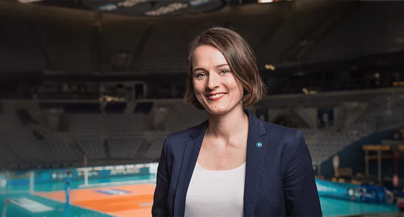 Julia Retzlaff lächelt selbstbewusst in einer modernen Sportarena und repräsentiert Vielfalt im Fußball.