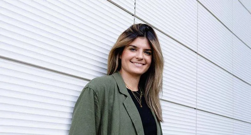 Katharina aus Kiel lächelt selbstbewusst vor einer modernen Wand und verkörpert die Zukunft des Fußballs.