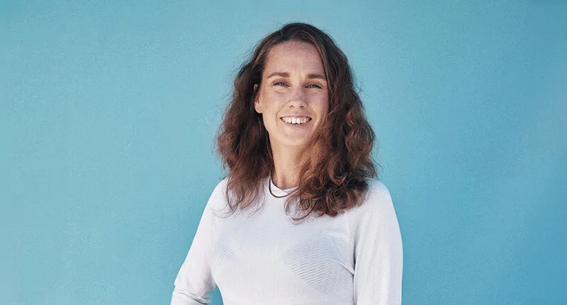 Lisa Waehrer lächelt selbstbewusst vor einem blauen Hintergrund, verkörpert die Leidenschaft für Fußball und Vielfalt.