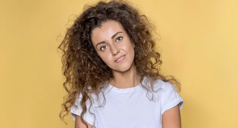 Rebecca Zenner präsentiert sich mit einem freundlichen Lächeln vor einem gelben Hintergrund und verkörpert die Vielfalt im Fußball.