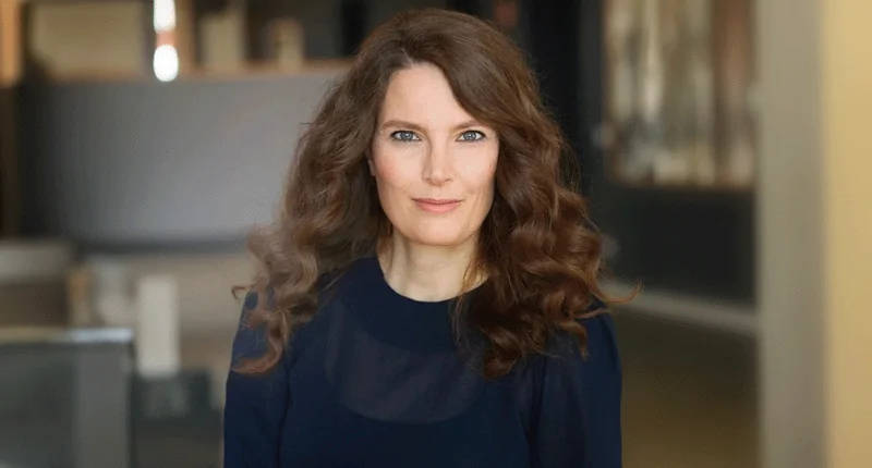 Eine Frau mit lockigem Haar blickt selbstbewusst in die Kamera und verkörpert die Vielfalt im Fußball.